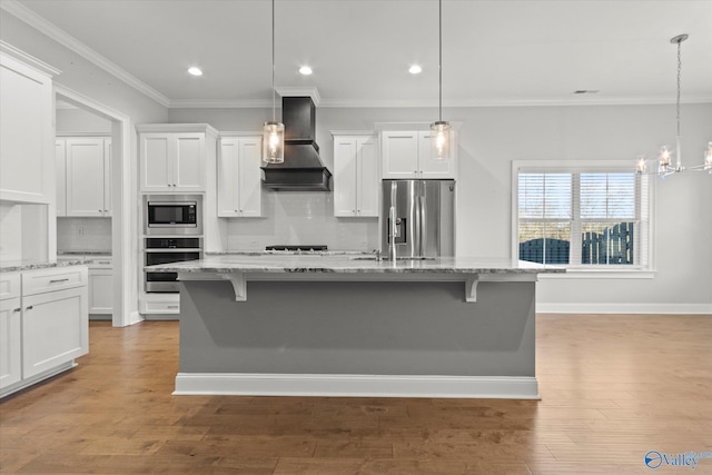 kitchen featuring appliances with stainless steel finishes, white cabinets, ornamental molding, and wall chimney range hood