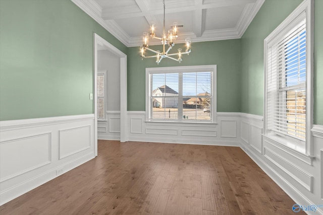 unfurnished dining area with a chandelier, beam ceiling, wood finished floors, and a wealth of natural light