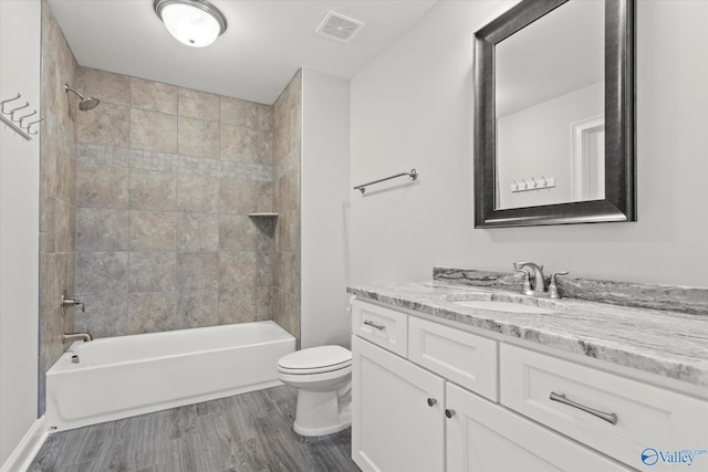 bathroom featuring visible vents, shower / bathing tub combination, toilet, vanity, and wood finished floors