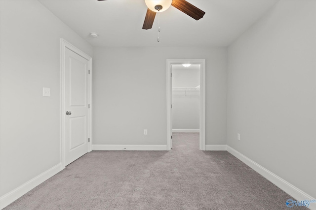 unfurnished bedroom with a ceiling fan, baseboards, a spacious closet, a closet, and carpet