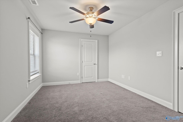 carpeted spare room with a ceiling fan, visible vents, and baseboards