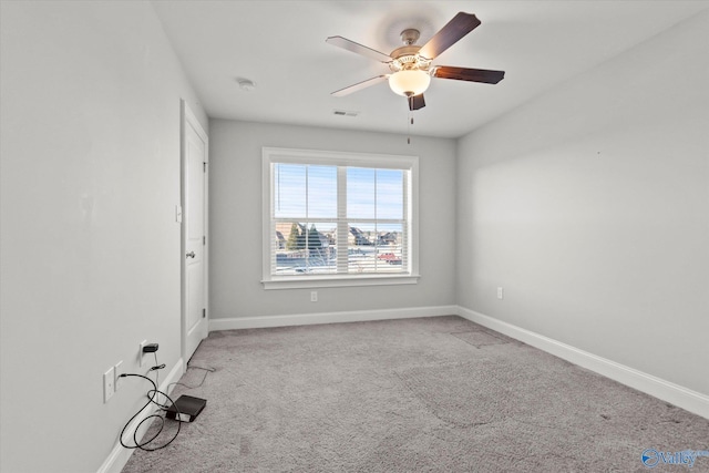 carpeted spare room featuring visible vents, ceiling fan, and baseboards