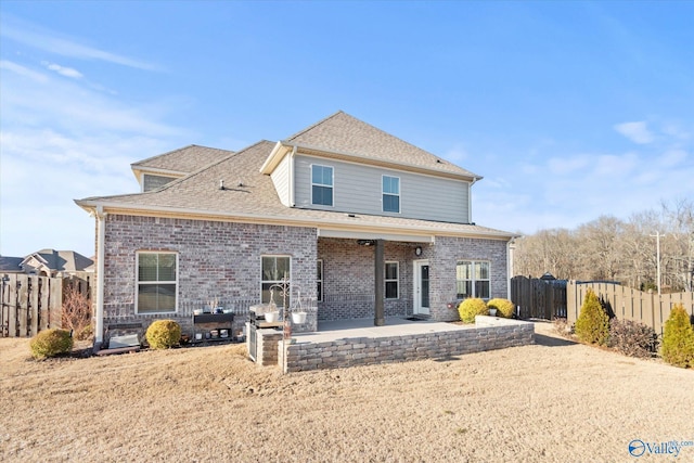 back of house featuring a patio area, roof with shingles, fence, and brick siding