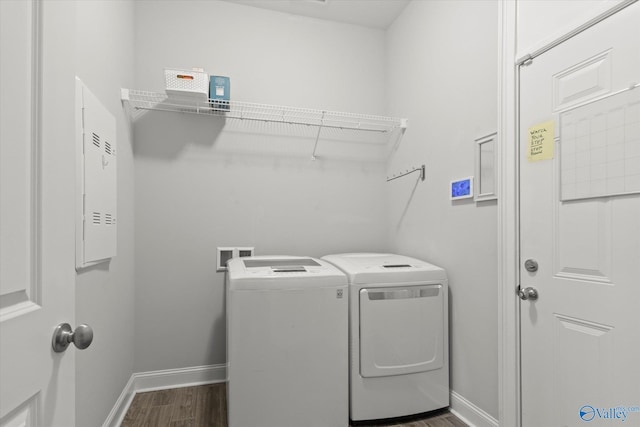 clothes washing area with dark wood-style floors, washer and dryer, laundry area, and baseboards