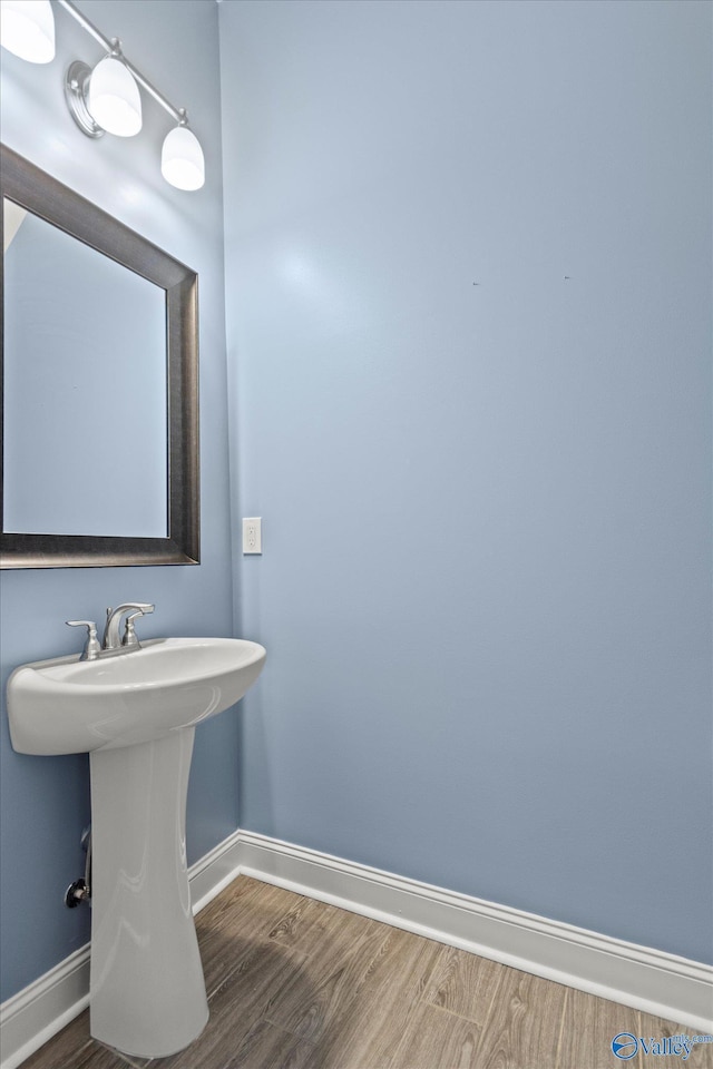 bathroom with a sink, baseboards, and wood finished floors