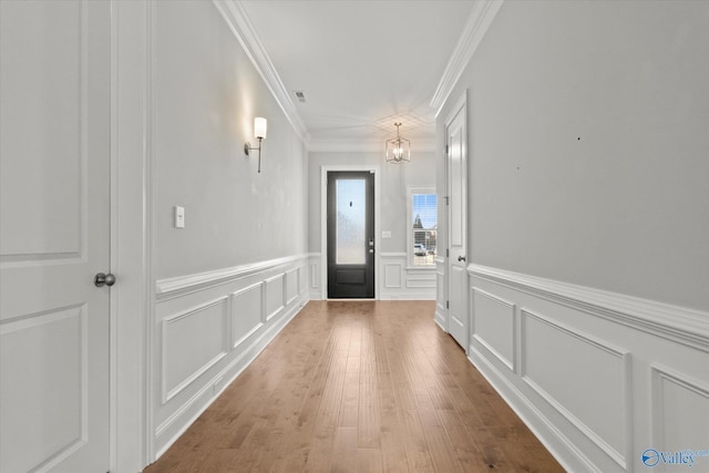 entryway with a decorative wall, wood finished floors, and crown molding