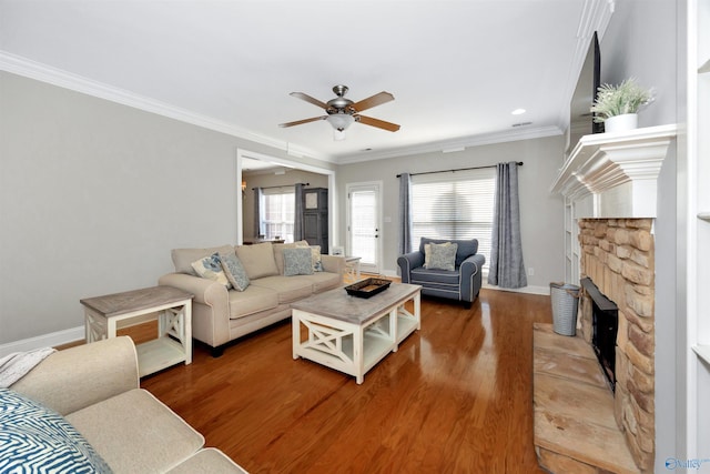 living area with ornamental molding, baseboards, a ceiling fan, a fireplace, and wood finished floors