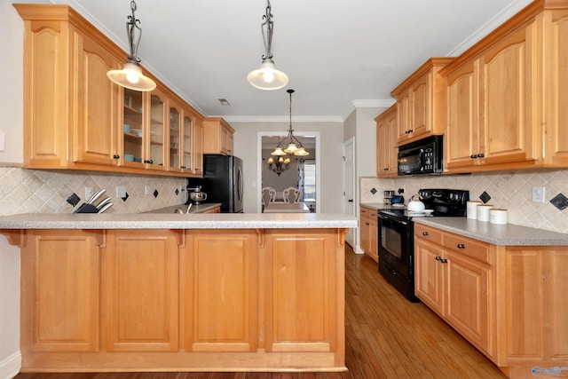 kitchen with light countertops, a breakfast bar area, a peninsula, glass insert cabinets, and black appliances
