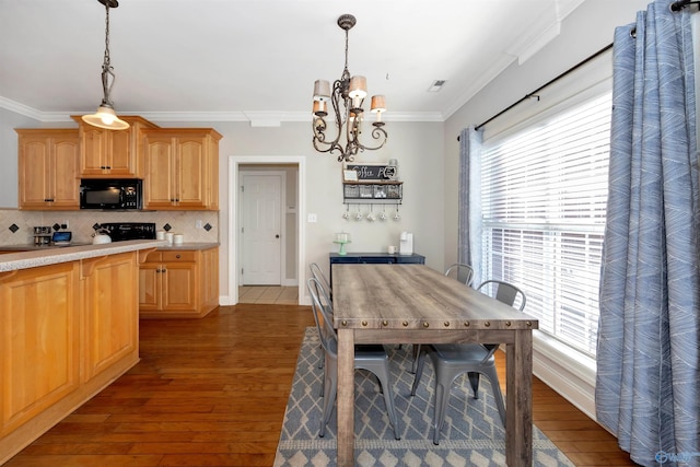 kitchen featuring light countertops, a chandelier, ornamental molding, black microwave, and hardwood / wood-style floors