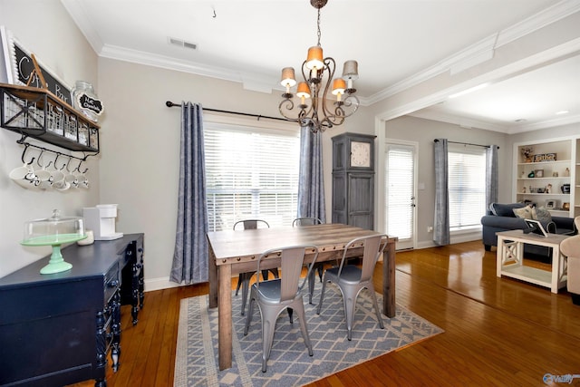 dining area featuring visible vents, crown molding, baseboards, hardwood / wood-style floors, and a notable chandelier
