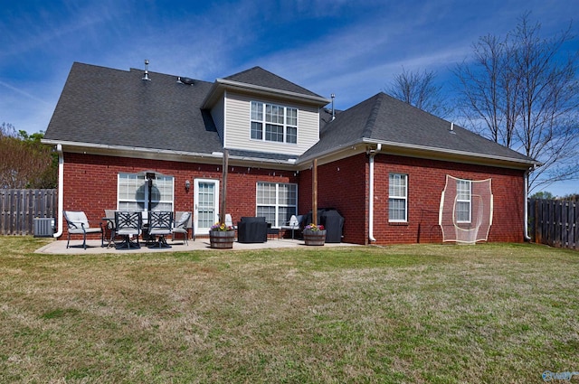 back of property with brick siding, a lawn, fence, and a patio