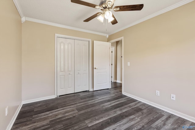 unfurnished bedroom with crown molding, baseboards, dark wood-style flooring, and a closet