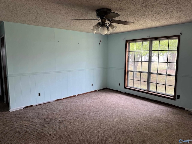 spare room with wainscoting, ceiling fan, carpet, and a textured ceiling