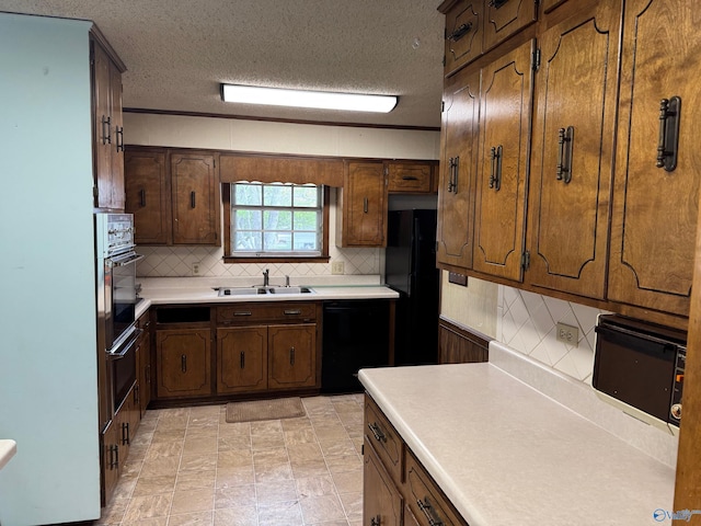 kitchen with light countertops, a sink, black appliances, and decorative backsplash