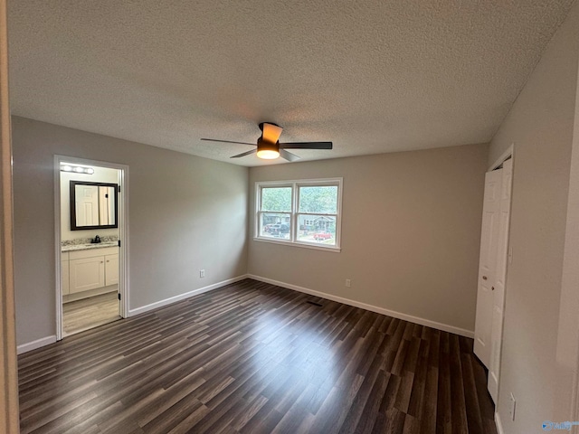 empty room featuring dark wood-type flooring, a textured ceiling, and ceiling fan