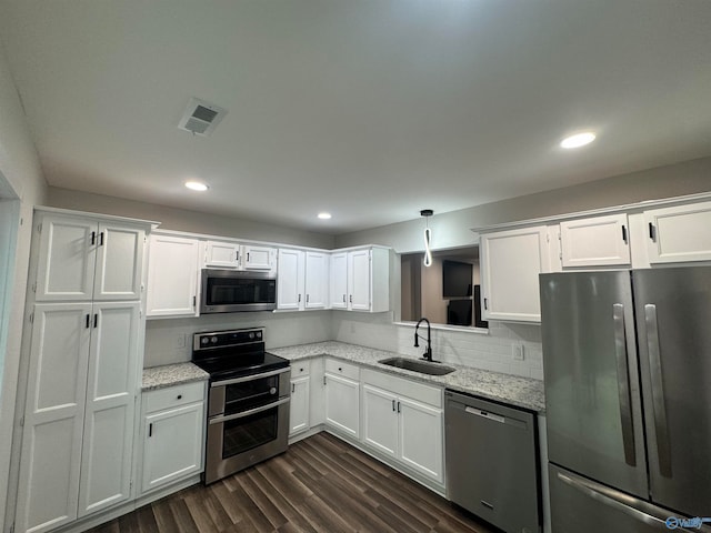 kitchen featuring white cabinetry, light stone counters, sink, dark hardwood / wood-style floors, and appliances with stainless steel finishes