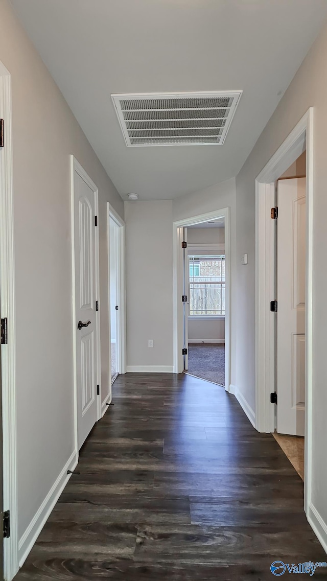 corridor featuring visible vents, baseboards, and wood finished floors