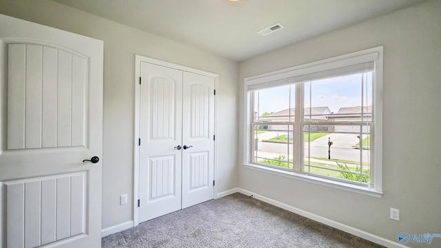 unfurnished bedroom with carpet flooring, baseboards, visible vents, and multiple windows