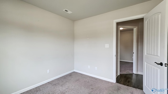 unfurnished room featuring baseboards, visible vents, and dark colored carpet