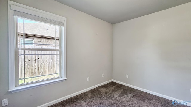 empty room with plenty of natural light, baseboards, and dark colored carpet