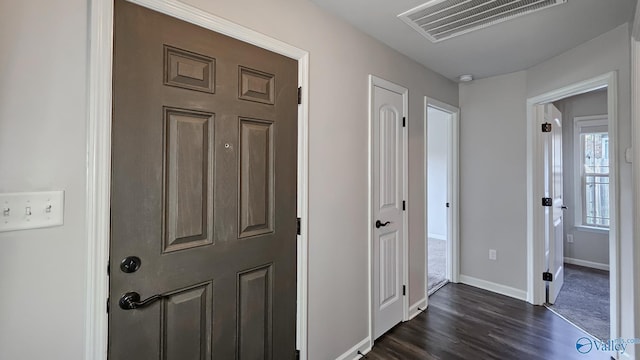 hallway with baseboards, dark wood-type flooring, and visible vents