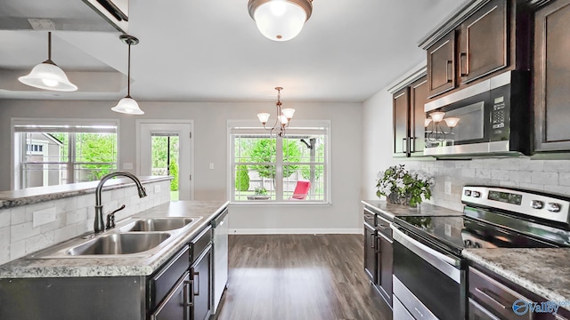 kitchen with dark brown cabinets, a sink, dark wood finished floors, backsplash, and stainless steel appliances