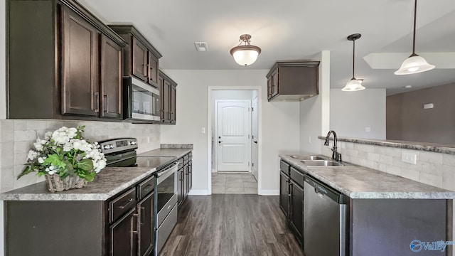 kitchen with dark brown cabinetry, backsplash, a sink, baseboards, and stainless steel appliances