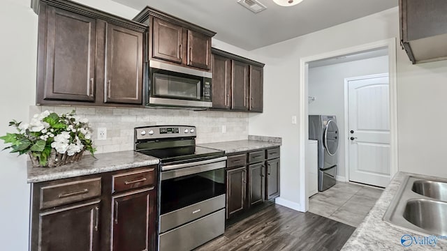 kitchen featuring independent washer and dryer, dark brown cabinets, appliances with stainless steel finishes, a sink, and visible vents