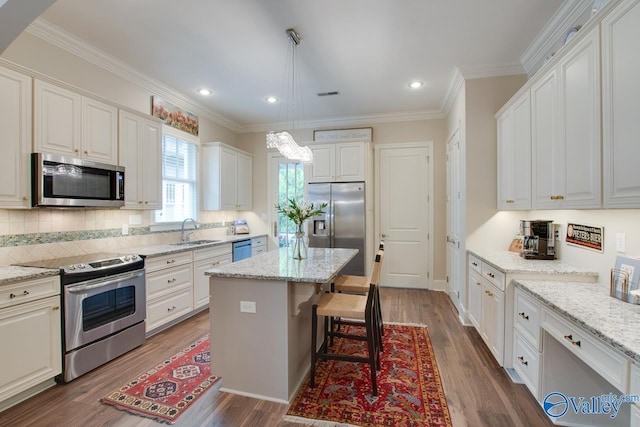 kitchen with sink, white cabinetry, a center island, hanging light fixtures, and stainless steel appliances