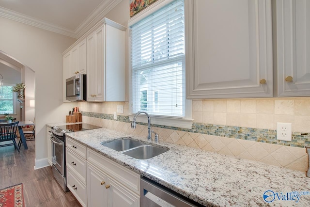 kitchen with sink, white cabinetry, crown molding, appliances with stainless steel finishes, and light stone countertops