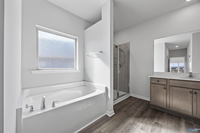 full bathroom featuring vanity, wood finished floors, baseboards, a shower stall, and a garden tub