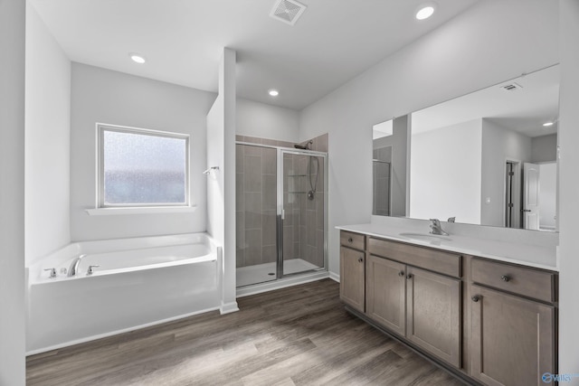 bathroom with vanity, wood finished floors, visible vents, a stall shower, and a bath