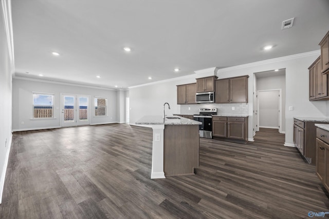 kitchen featuring tasteful backsplash, dark wood finished floors, open floor plan, appliances with stainless steel finishes, and a sink