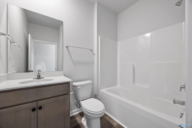 full bath featuring vanity, wood finished floors, baseboards, tub / shower combination, and toilet