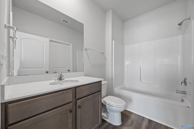 full bath featuring visible vents, toilet, wood finished floors, vanity, and shower / bathtub combination