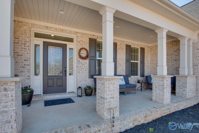 doorway to property featuring covered porch and brick siding