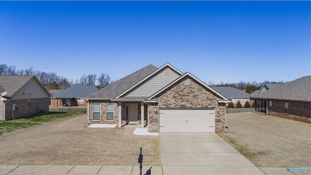 view of front of house with driveway, a garage, fence, and brick siding