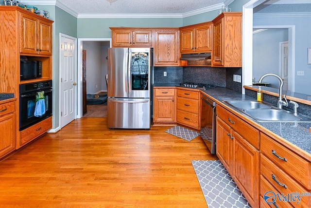 kitchen with ornamental molding, light wood-style floors, a sink, under cabinet range hood, and black appliances