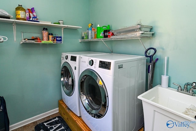 laundry room with laundry area, baseboards, tile patterned floors, washer and dryer, and a sink