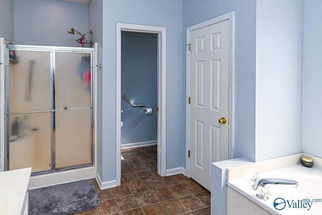 bathroom with a stall shower, baseboards, and a bath