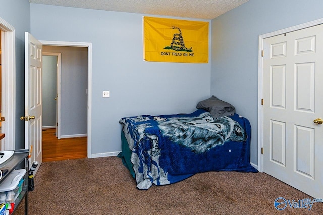 bedroom with a textured ceiling, carpet floors, and baseboards