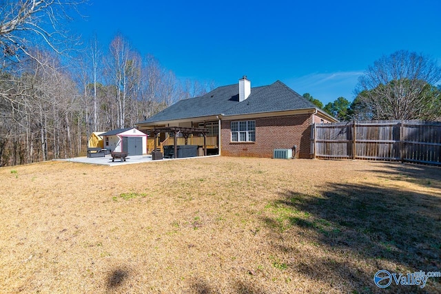 rear view of house with a lawn, a patio, a chimney, an outdoor structure, and brick siding