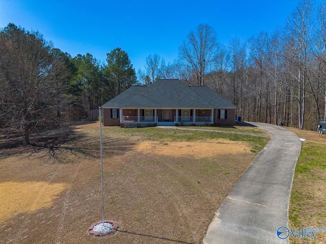 view of front of house with covered porch, brick siding, and a front yard