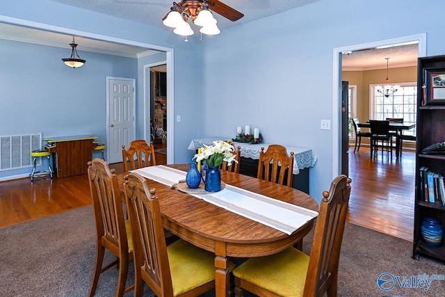 dining space featuring a textured ceiling, wood finished floors, carpet flooring, visible vents, and crown molding