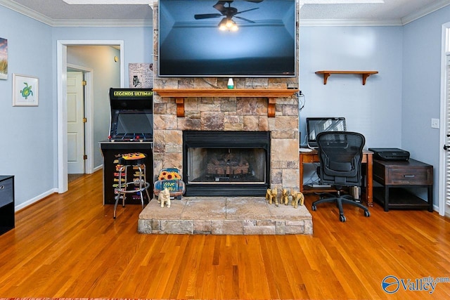 living area with wood finished floors, crown molding, and a stone fireplace