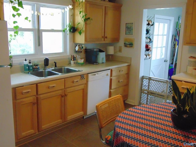 kitchen featuring dark tile patterned floors, white appliances, and sink