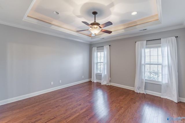 spare room featuring a tray ceiling, ceiling fan, dark wood-type flooring, and ornamental molding