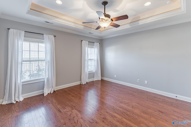 unfurnished room with dark wood-type flooring, a raised ceiling, and a healthy amount of sunlight