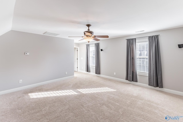 carpeted spare room with ceiling fan and vaulted ceiling