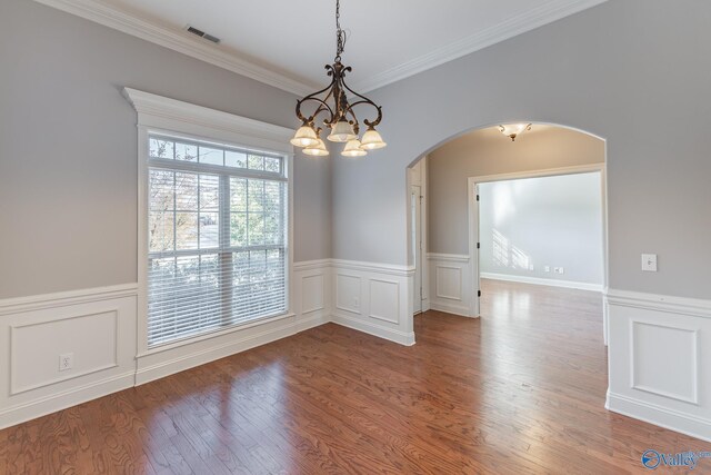 spare room featuring hardwood / wood-style flooring, a notable chandelier, and crown molding